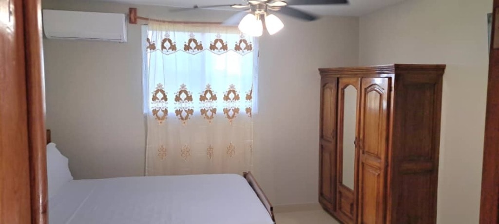 Guest bedroom with ceiling fan, AC unit, lace curtains and solid wood wardrobe