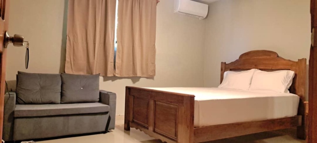Air-conditioned guest room with wooden bed and sofa seating