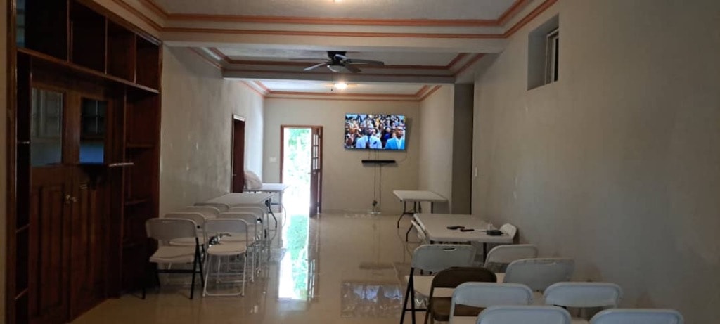 Spacious event room with folding tables, chairs and wall-mounted TV