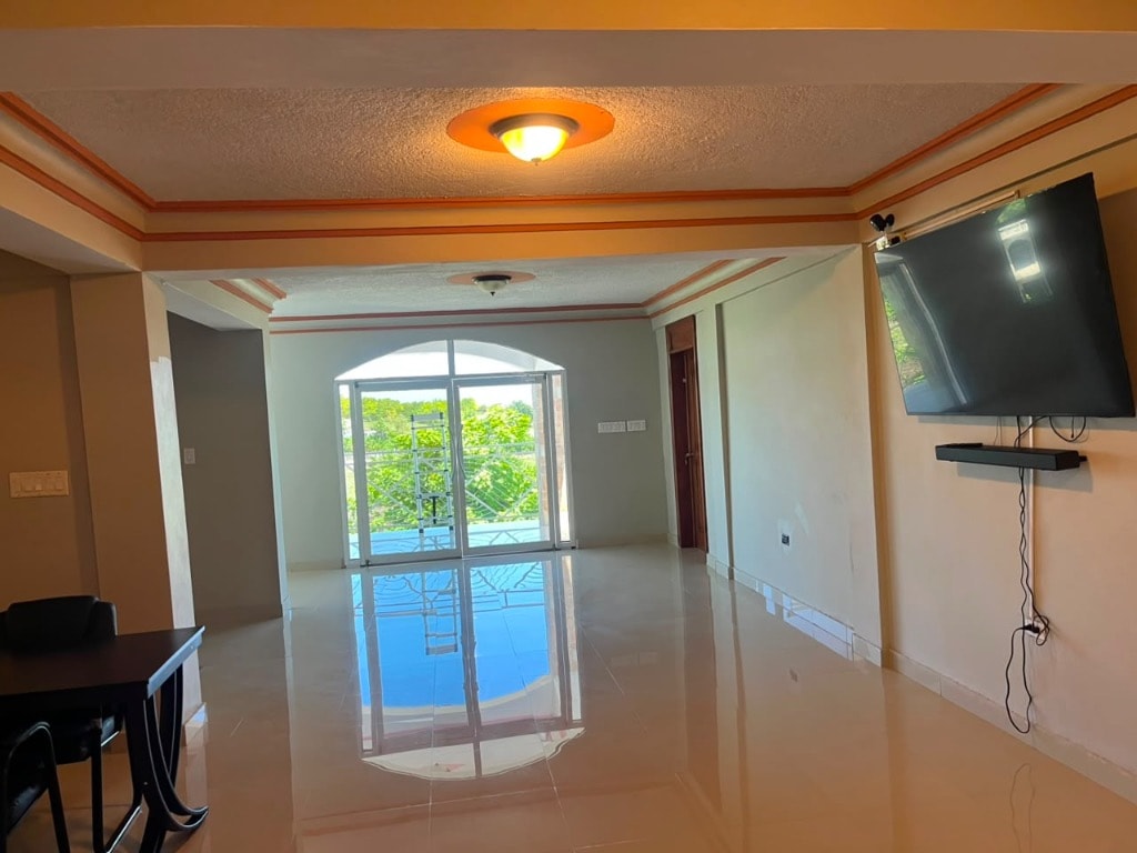 Villa interior living room with pool view through arched glass doors