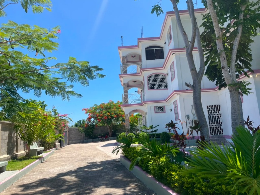 Villa Rêve Créole — driveway approach with lush tropical gardens and pink-trimmed facade