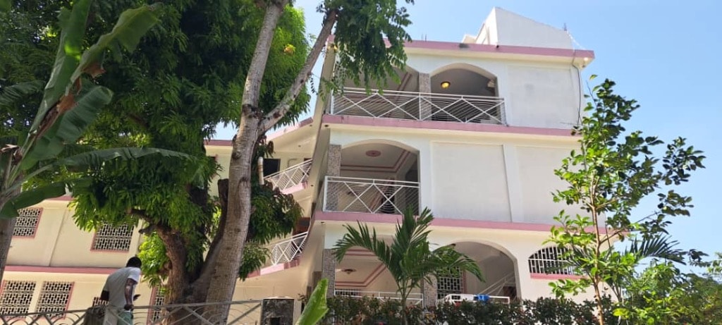 Villa Rêve Créole — three-story pink and white exterior with balconies and tropical trees